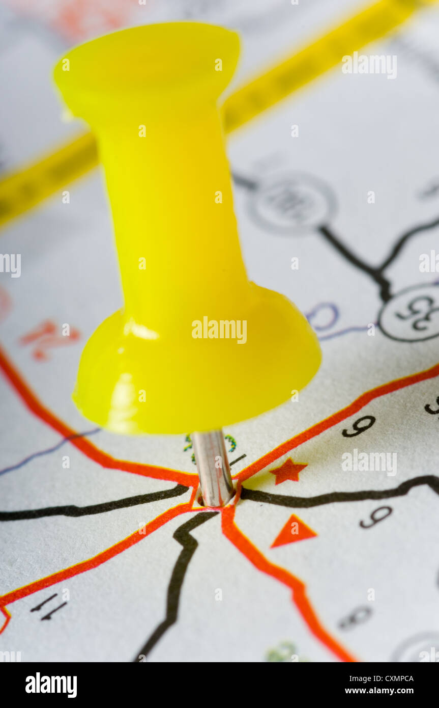 Yellow pushpin on map marking an intersection of several roads Stock Photo