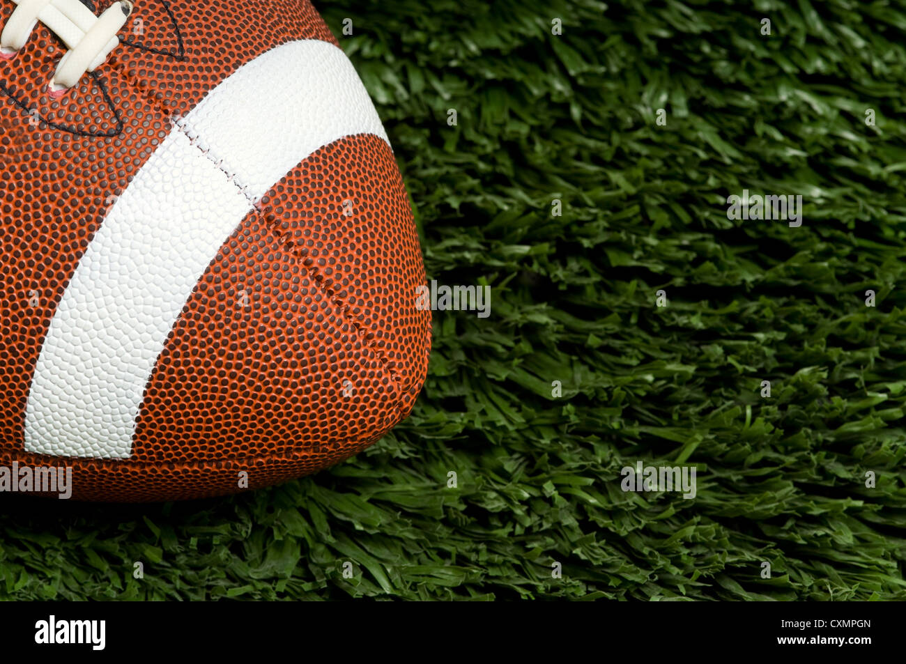 American football on green artificial grass field, copy space to the right Stock Photo
