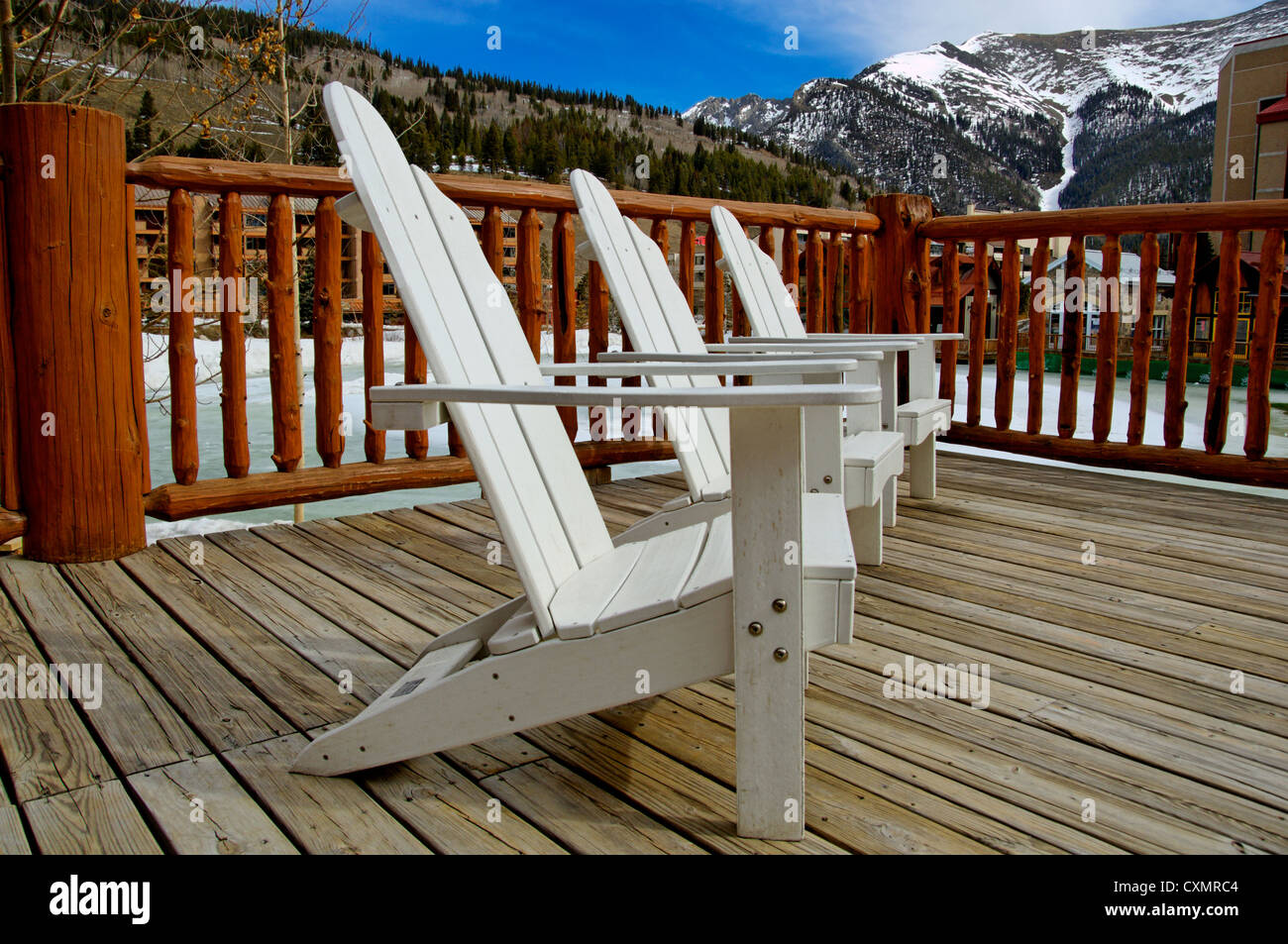 white deck chairs in the mountains on a sunny, blue sky day at a ski