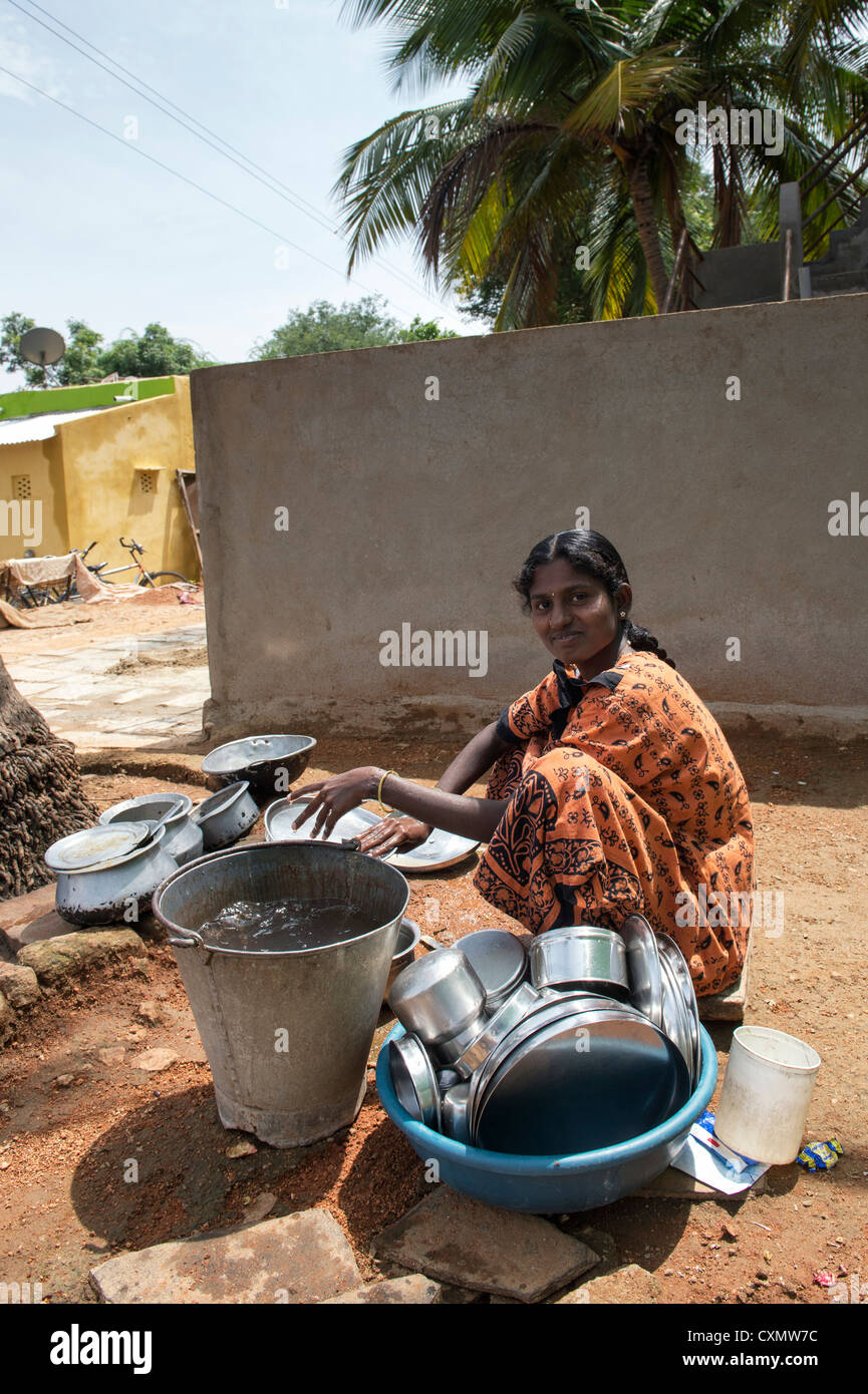 Young Indian mother washing dishes outside their rural indian village home. Andhra Pradesh, India Stock Photo