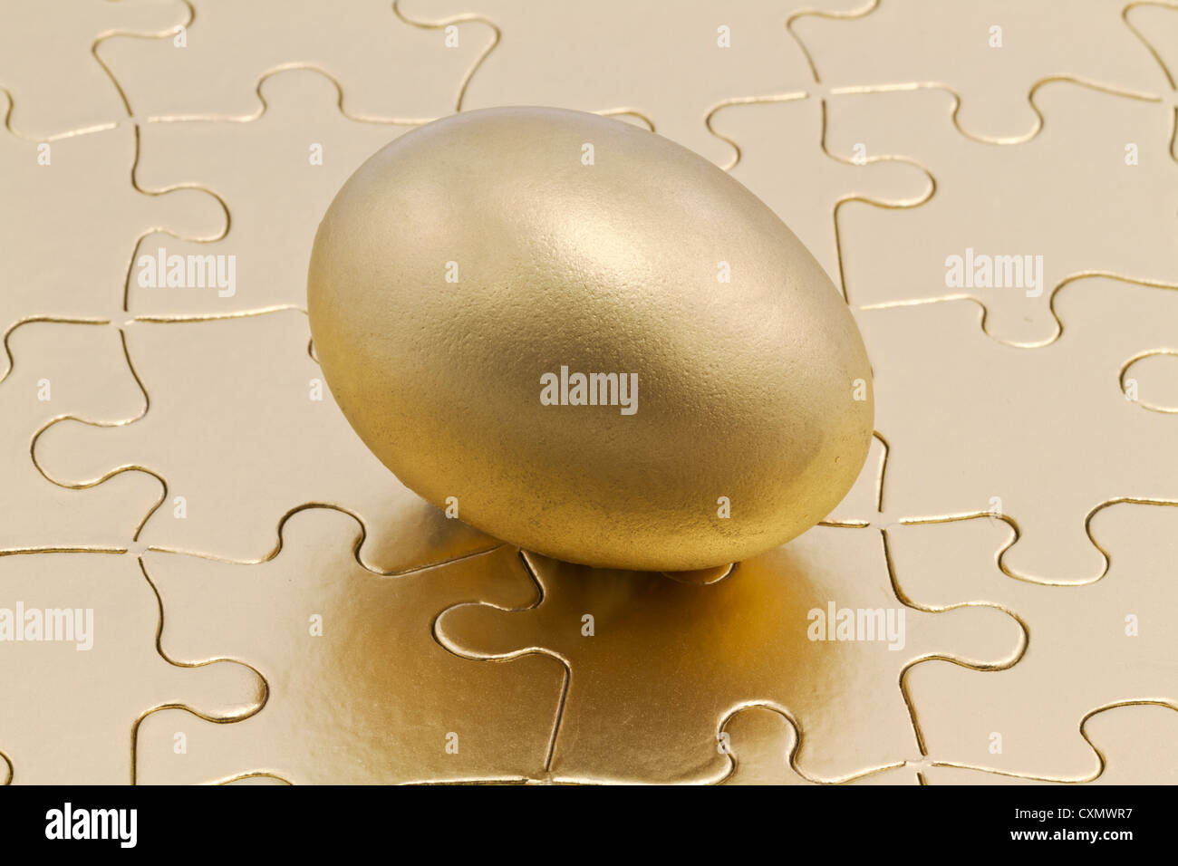 Golden nest eggs sits on metallic gold puzzle; savings is the key to the financial and business puzzle. Stock Photo