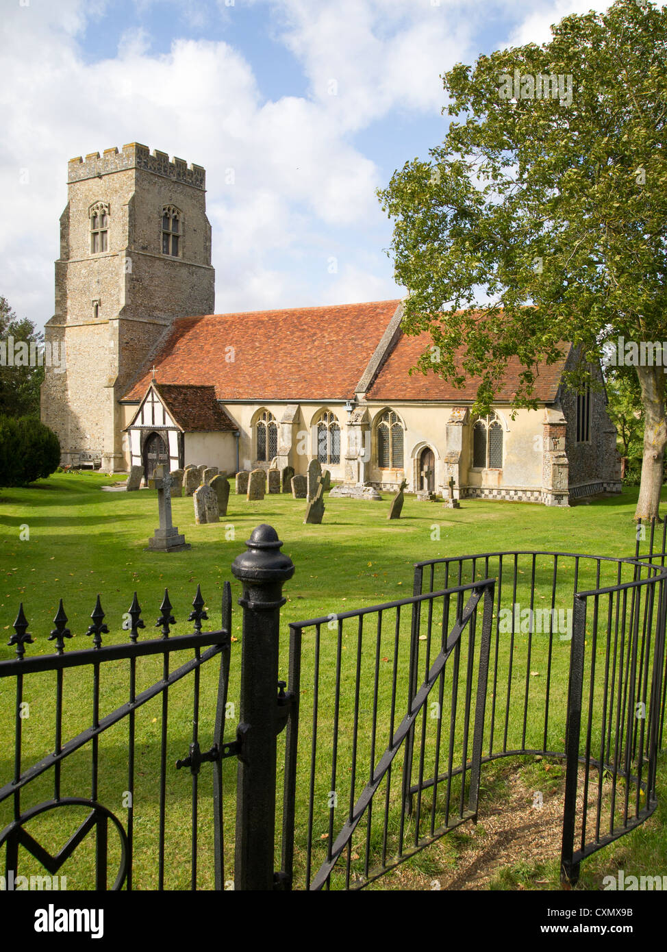 An old English church pictured with a wrought iron kissing gate and fence in the foreground. Stock Photo