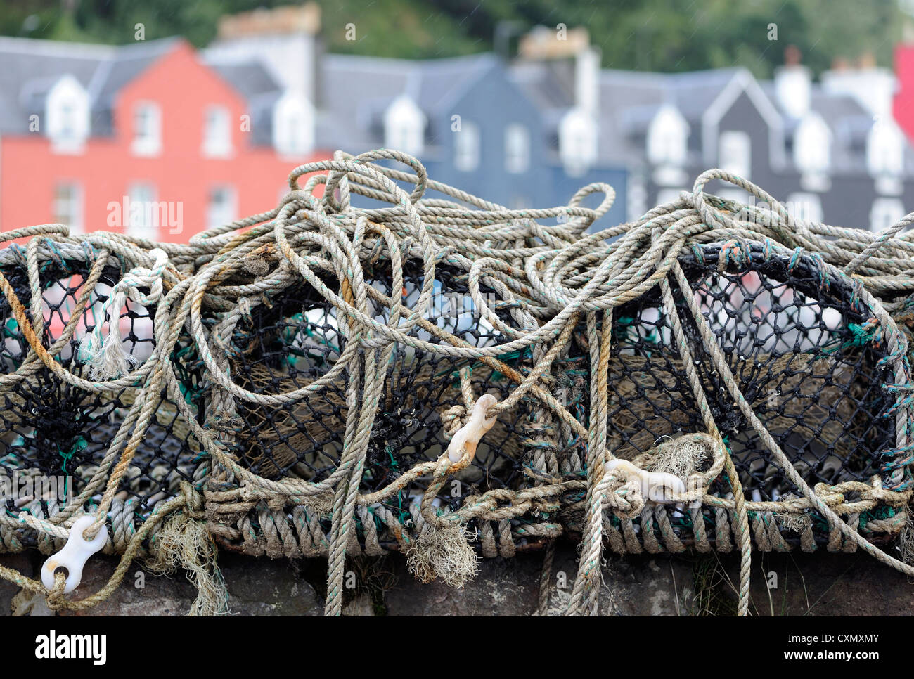 Crab pots on the harbour wall with the the brightly painted houses of Tobermory's Main Street in the background. Stock Photo