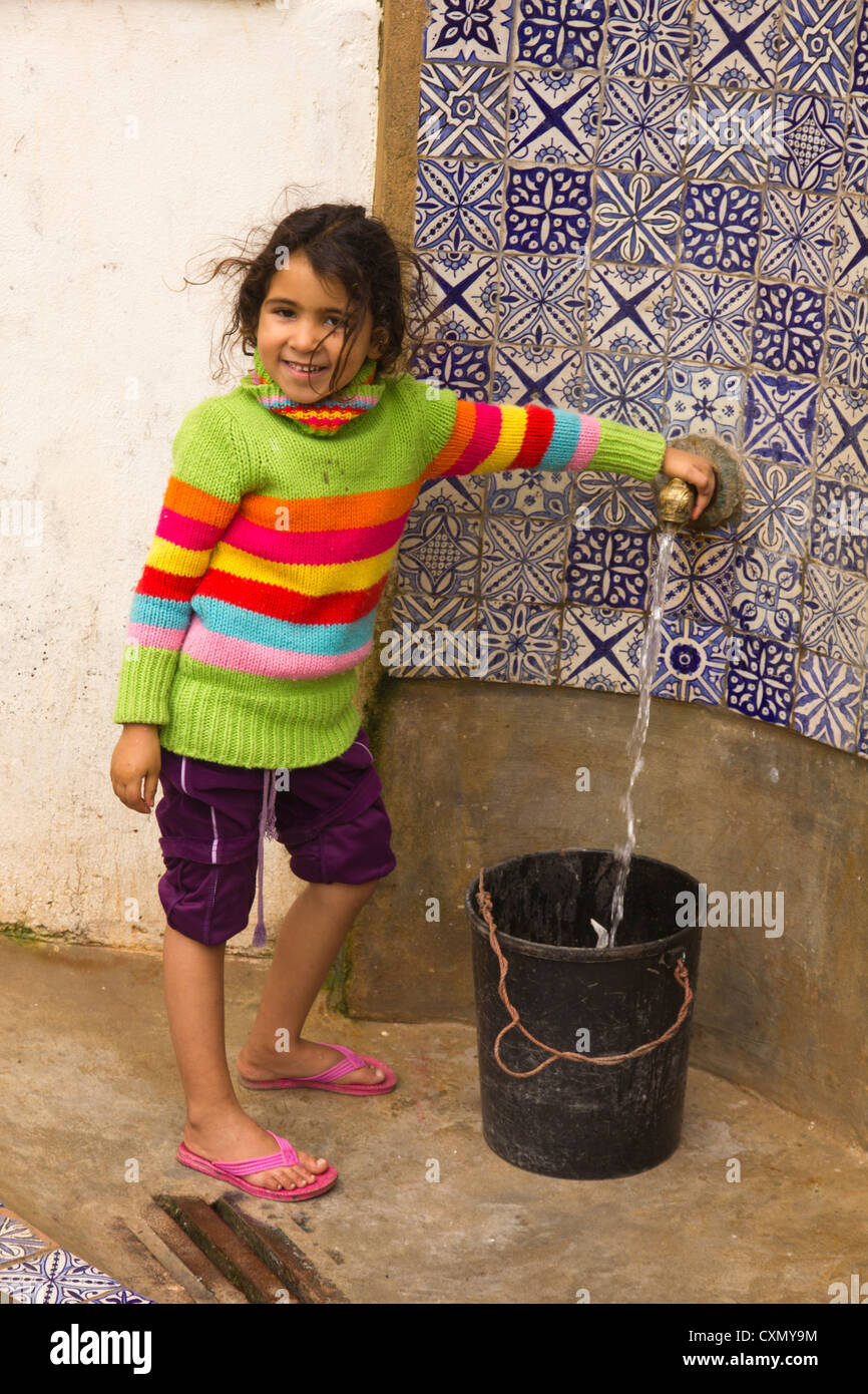 Young girl filling her bucket with water from a public water supply Fez