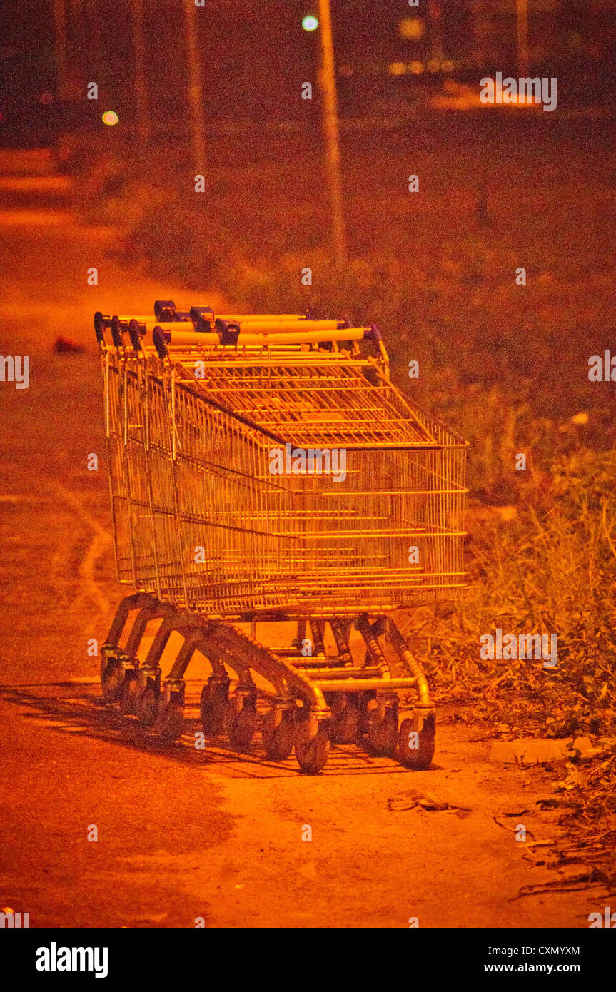 shopping carts are abandoned in area of darkness, to convey danger or crime concepts, images are pushed with visible noise. Stock Photo