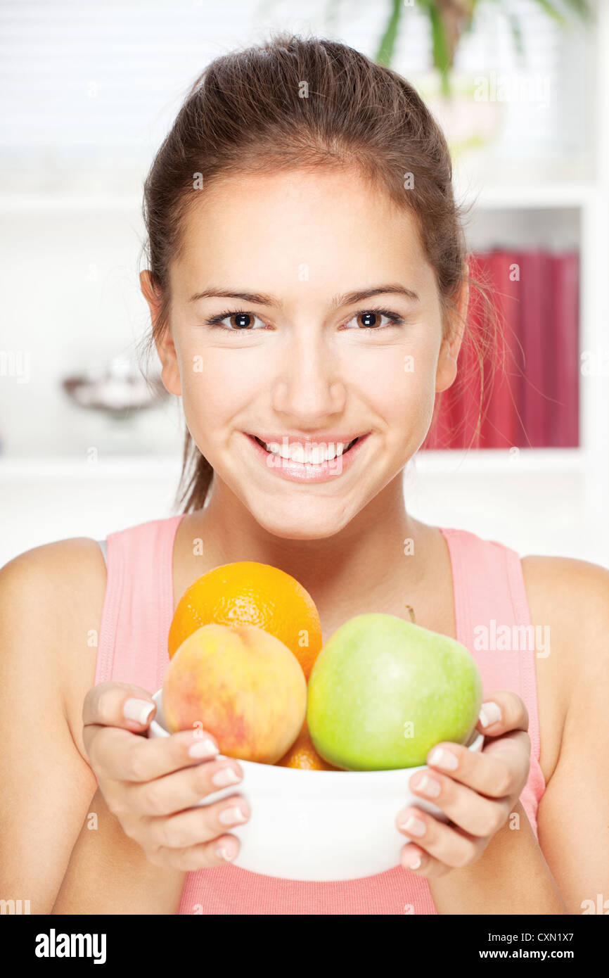 Portrait of young happy smiling woman with bowl of fruits Stock Photo