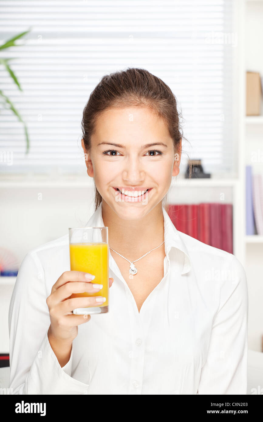 Young smiling woman holding glass of orange juice at home Stock Photo