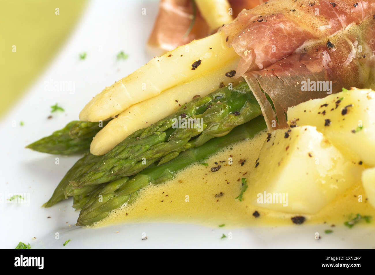 White and green asparagus wrapped in thin ham slices with Hollandaise