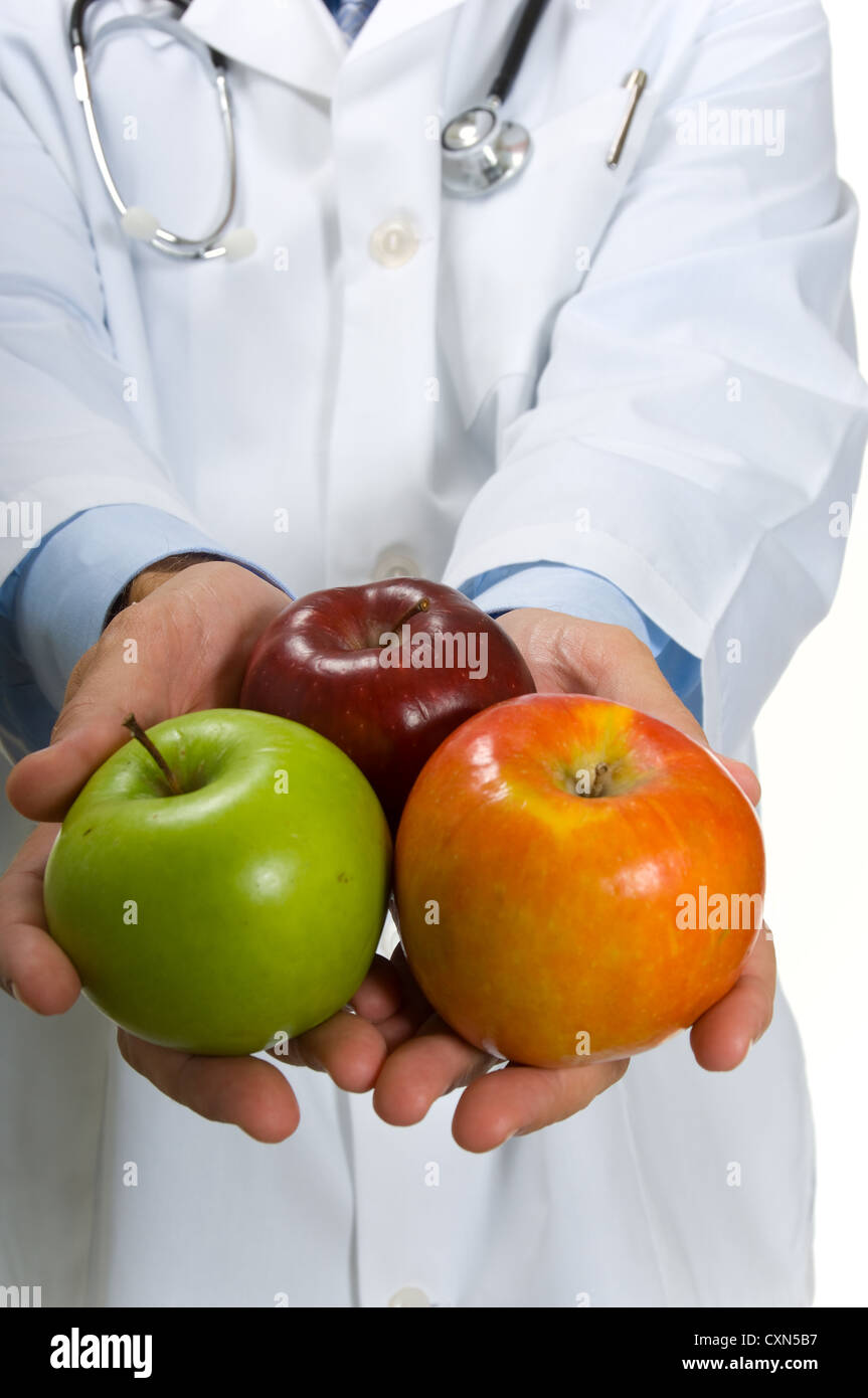 Physician in a white lab coat with stethoscope holding out apples Stock ...
