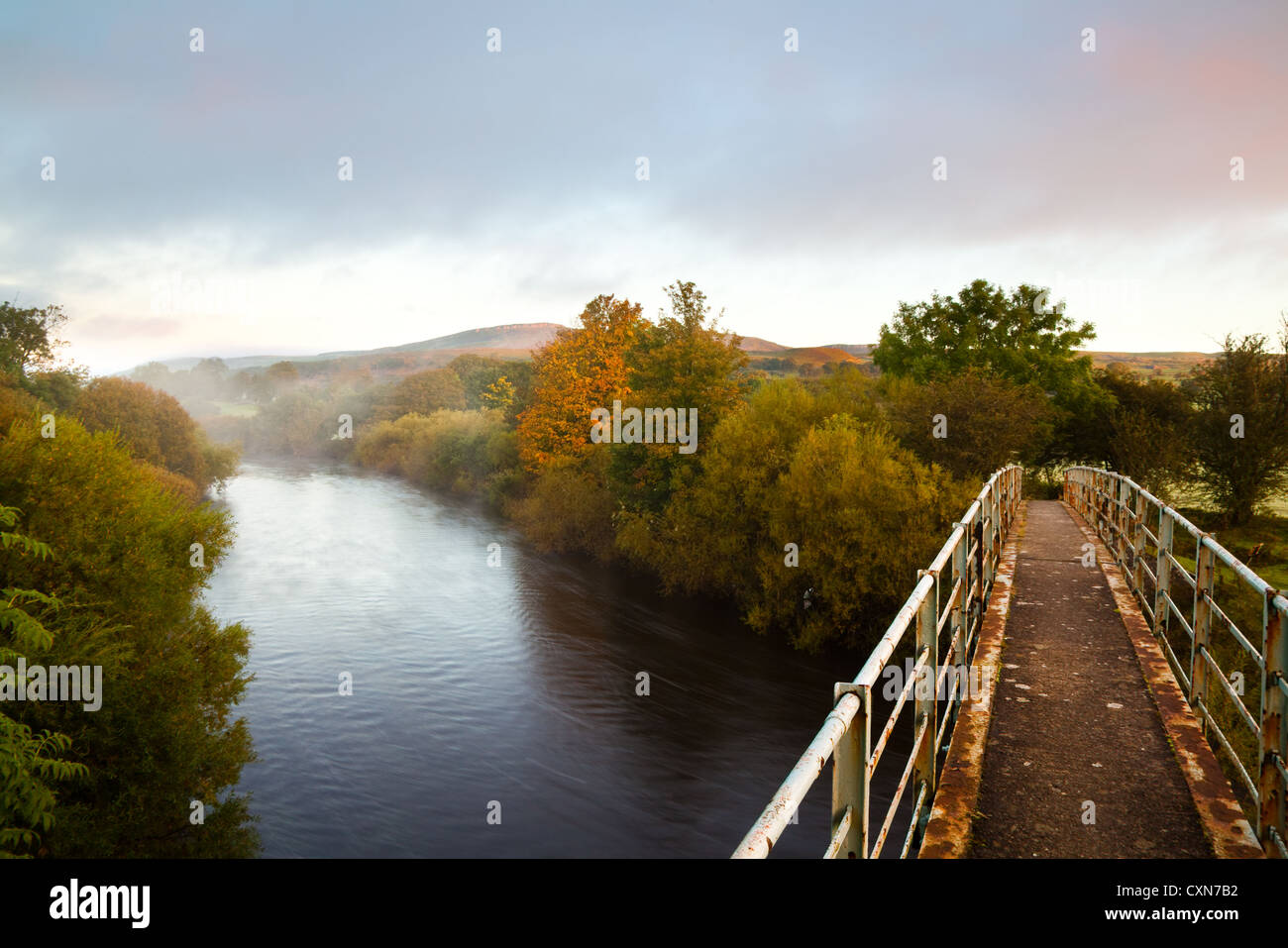 Iron walkers footbridge with riverside view of Autumn trees on the River Ure near Asygarth, North Yorkshire Dales and National Park, UK Stock Photo
