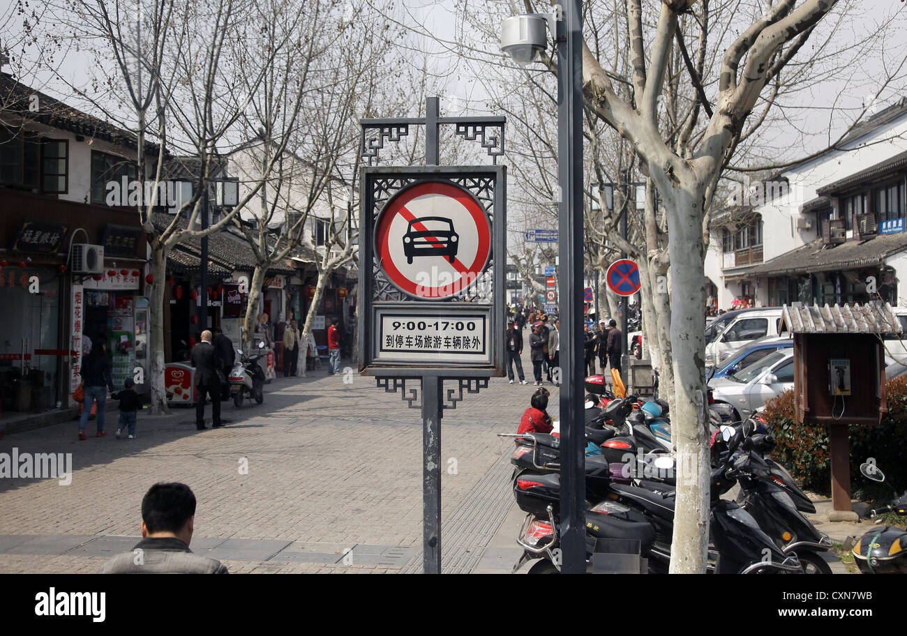 It's a photo of a street in China forbidden for cars. It's pedestrian only. We can see many houses and shops an plane trees Stock Photo