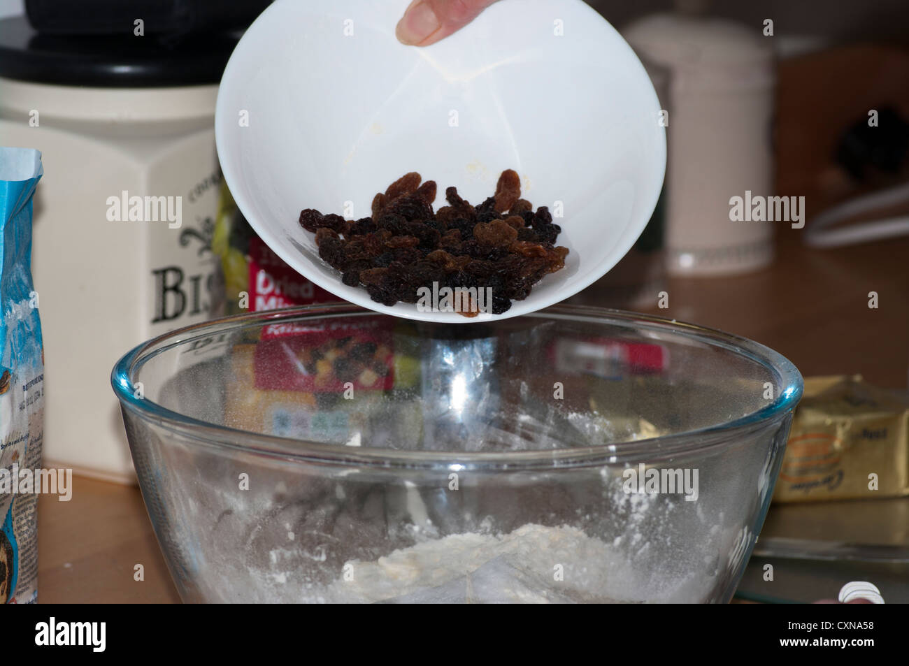 Cook Adding Dried Fruit To A Cake Mix In A Bowl Home Baking Stock Photo