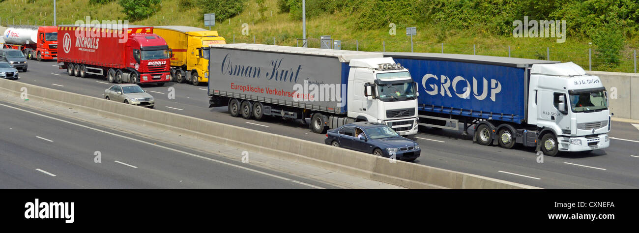 Concrete crash barrier and busy traffic on 4 lane section of M25 motorway with articulated lorries overtaking Stock Photo