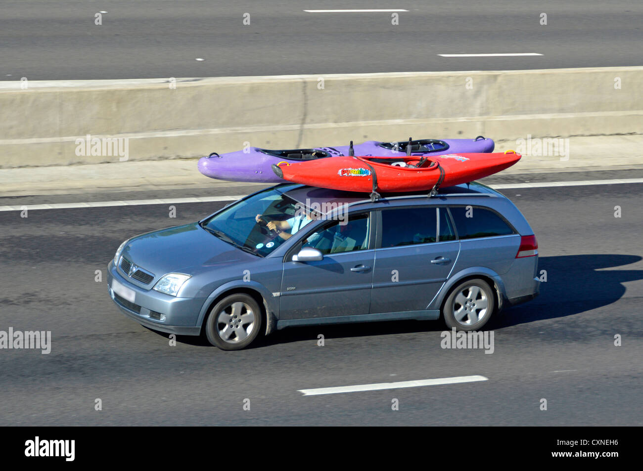 Car driving along motorway with canoe kayaks on roof Stock Photo