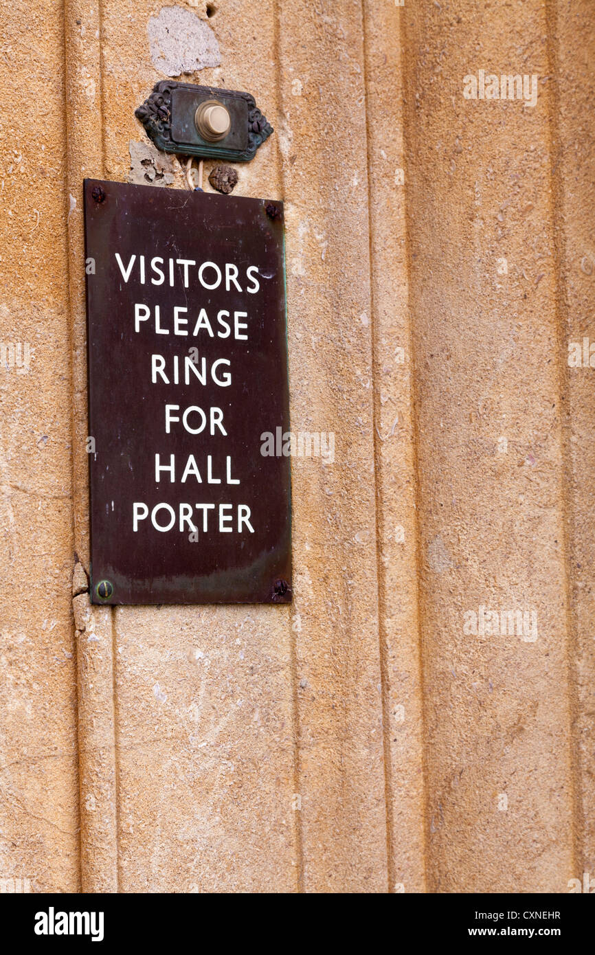 'Visitors please ring for hall porter' sign by door bell button. Stock Photo