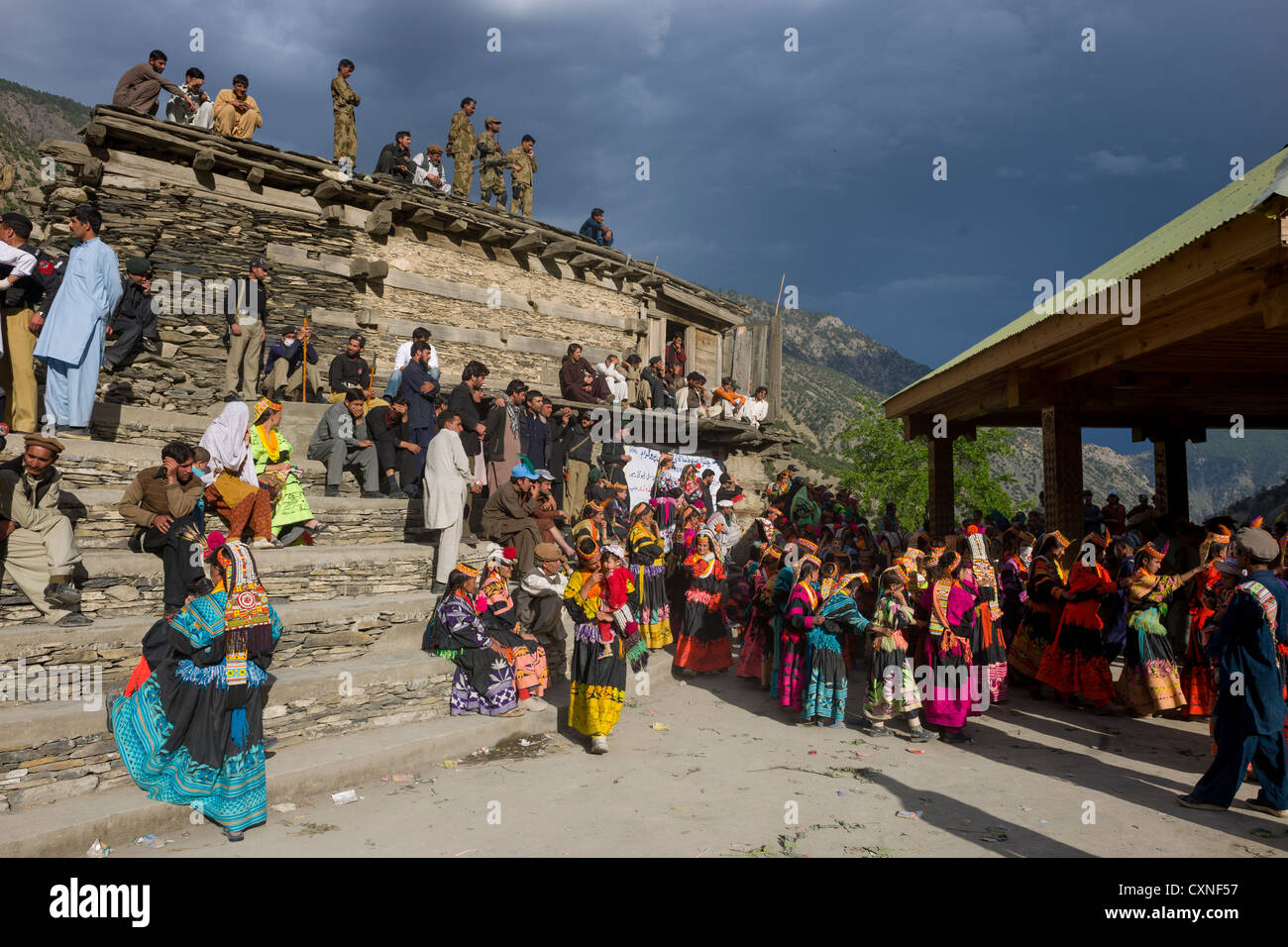 Kalash women and girls overlooked by security forces at the Grum Village Charso (dancing ground), Kalash Joshi (Spring Festival), Rumbur Valley, Chitral, Khyber-Pakhtunkhwa, Pakistan Stock Photo