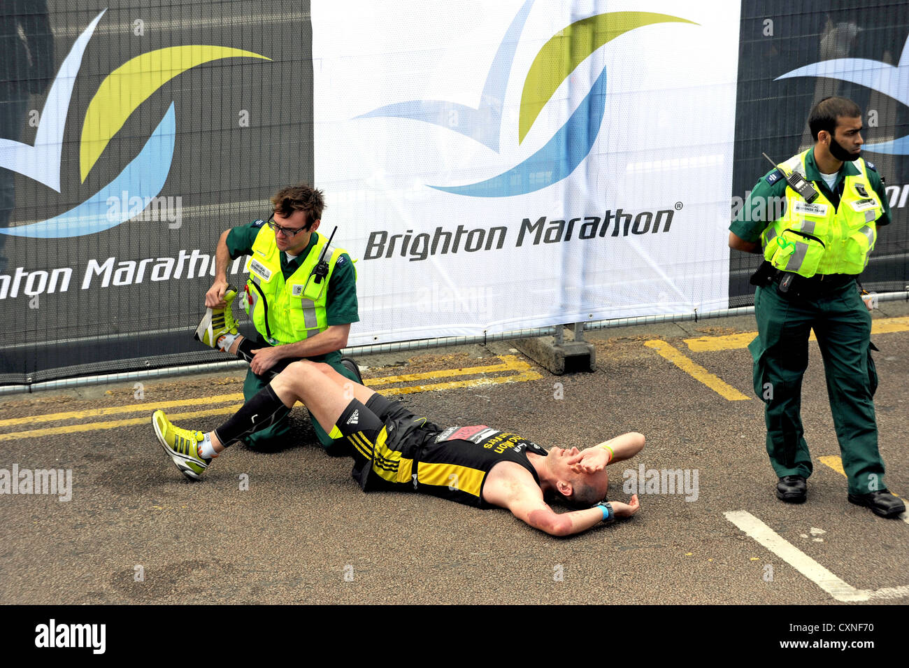 A runner gets treatment for cramp after crossing the finish line during