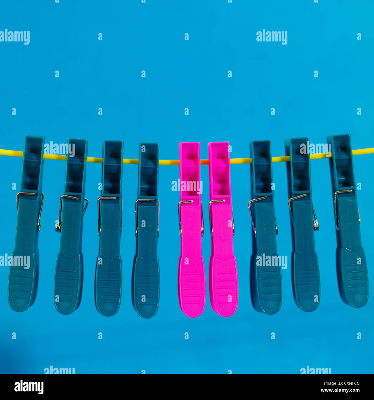 Plastic laundry pegs hanging from yellow plastic clothes line on blue
