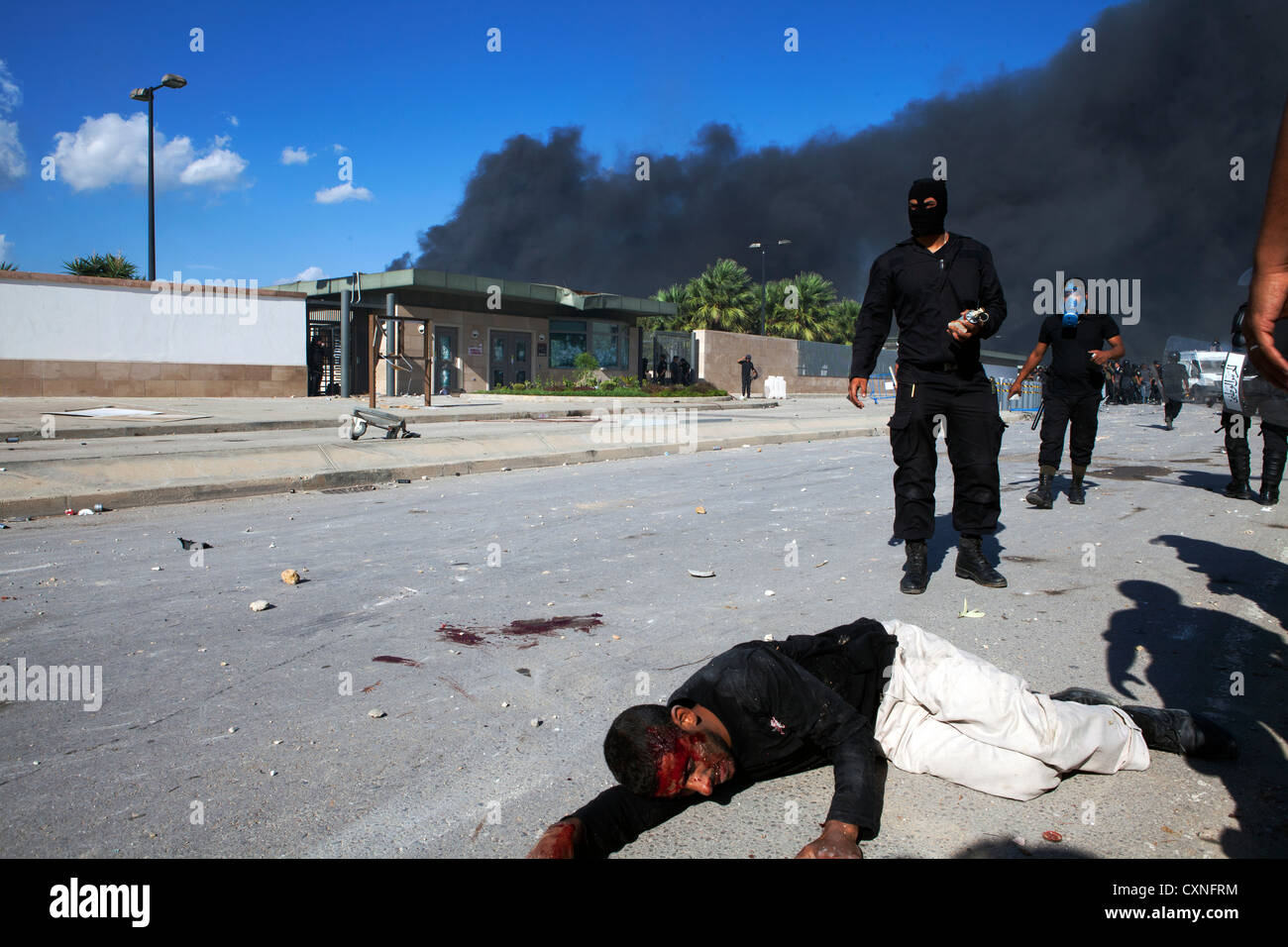 A protester lays unconscious on the ground outside the US embassy in Tunis after being run over by a armored personnel carrier. Stock Photo