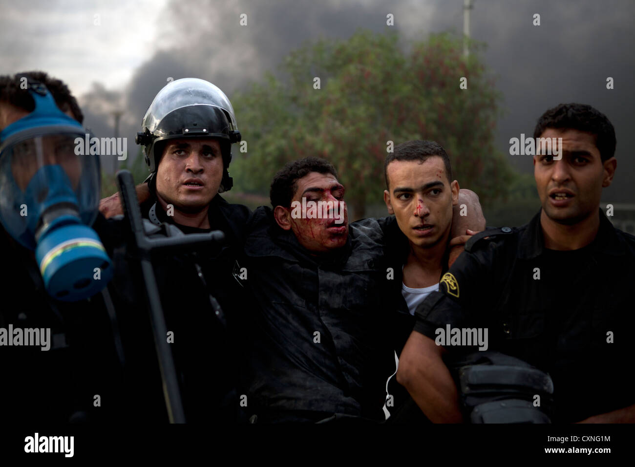 Police carry a wounded colleague to safety during violent demonstration that lead to the storming of the US embassy in Tunis Stock Photo