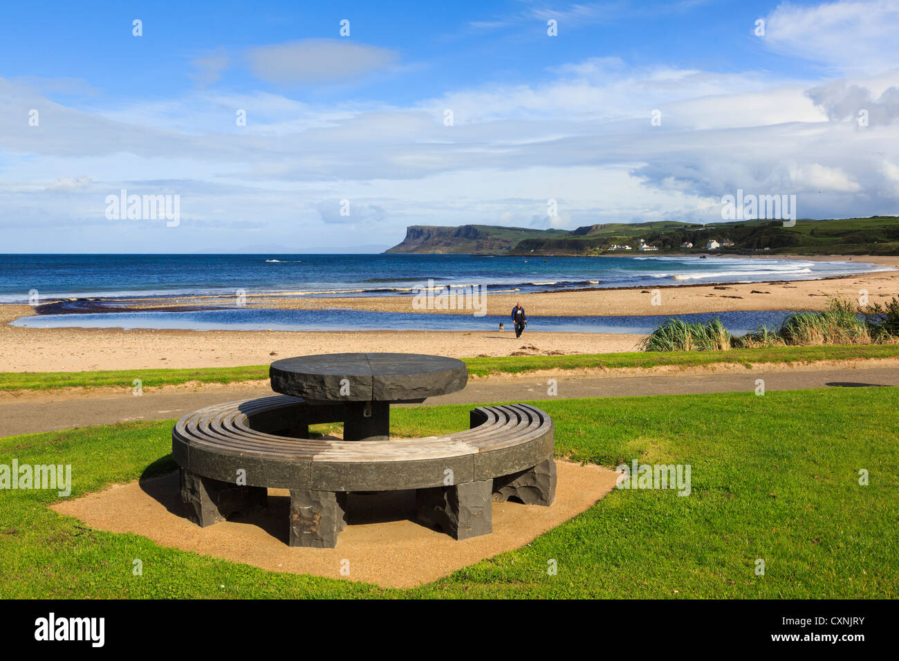 Picnic table on seafront and view across sandy beach to Fair Head or Benmore headland. Ballycastle Co Antrim Northern Ireland UK Stock Photo
