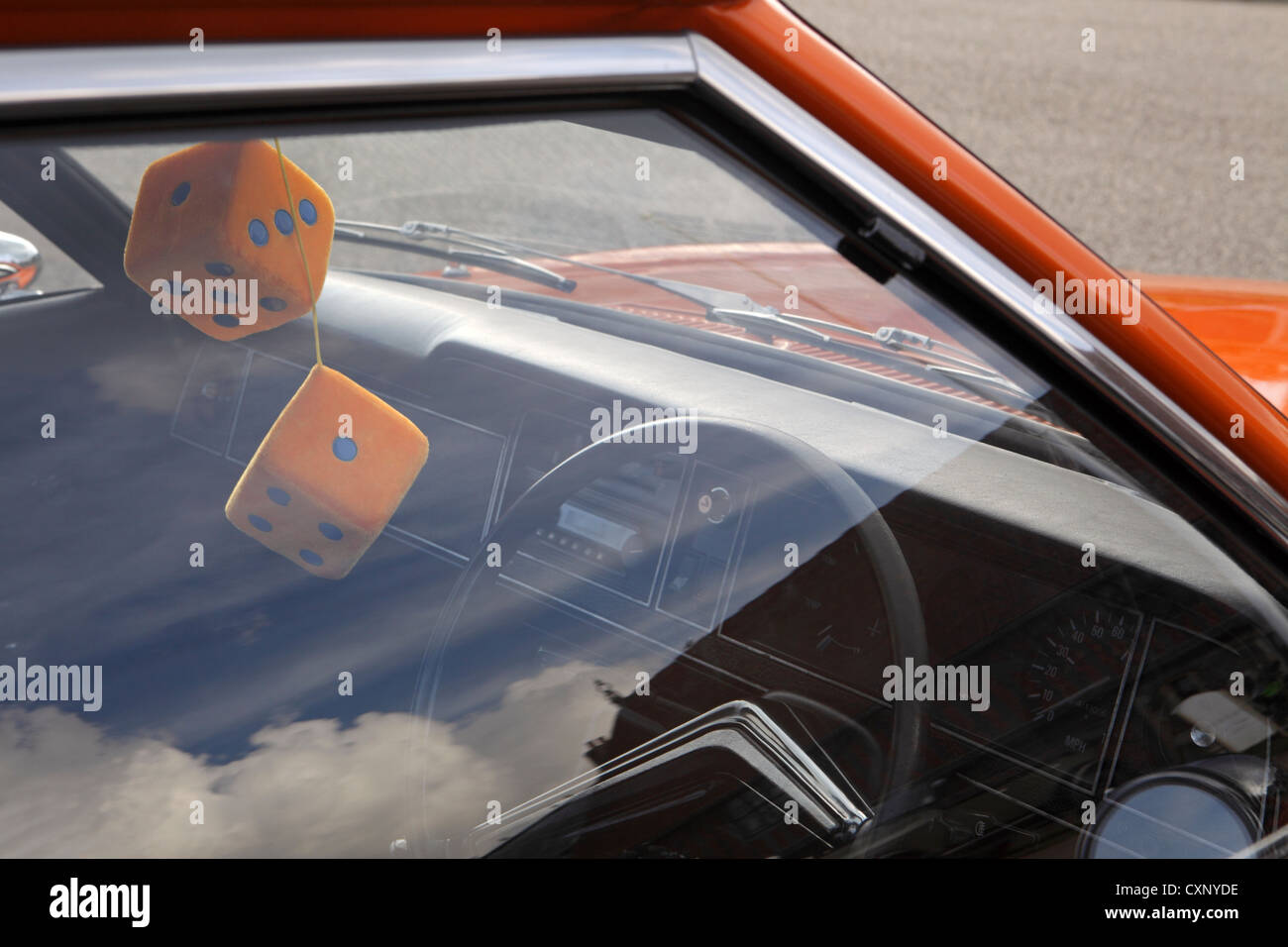 Pair large orange fuzzy furry dice hanging from rear view mirror, restored orange Ford Cortina Mark 3, Suffolk, UK Stock Photo
