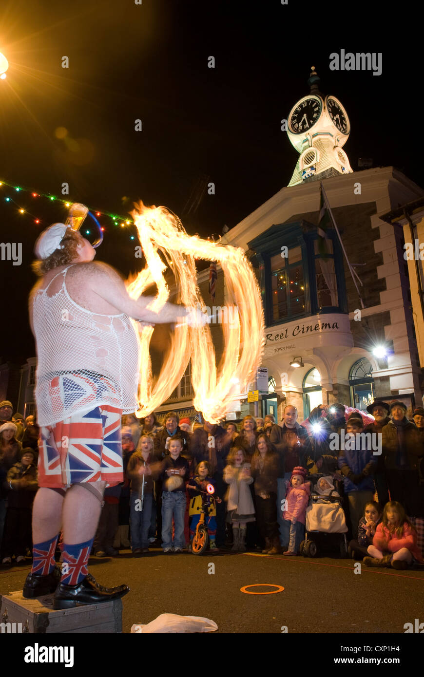 A Street entertainer performs to a group of Christmas shoppers outside the Reel Cinema in Kingsbridge, Devon, in the UK. Stock Photo