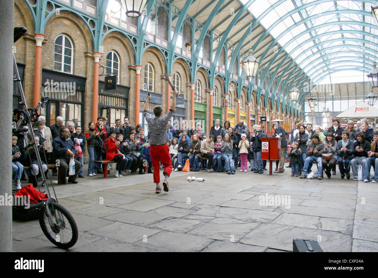 A juggling street entertainer performing to crowds indoor at Covent