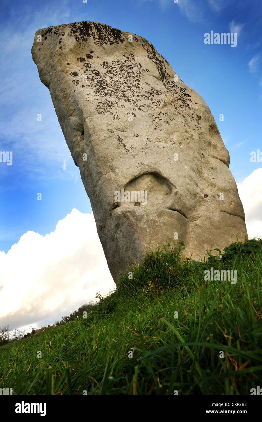 A single standing stone - part of a historical monument situated in grass field seen from below Stock Photo