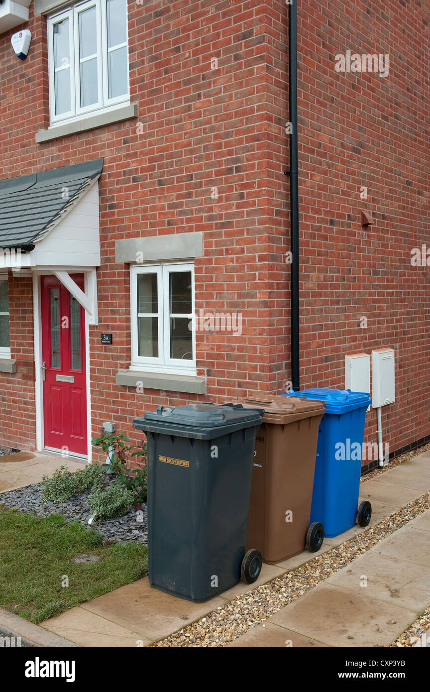 Assortment of wheelie bins lined up on a drive outside a house in