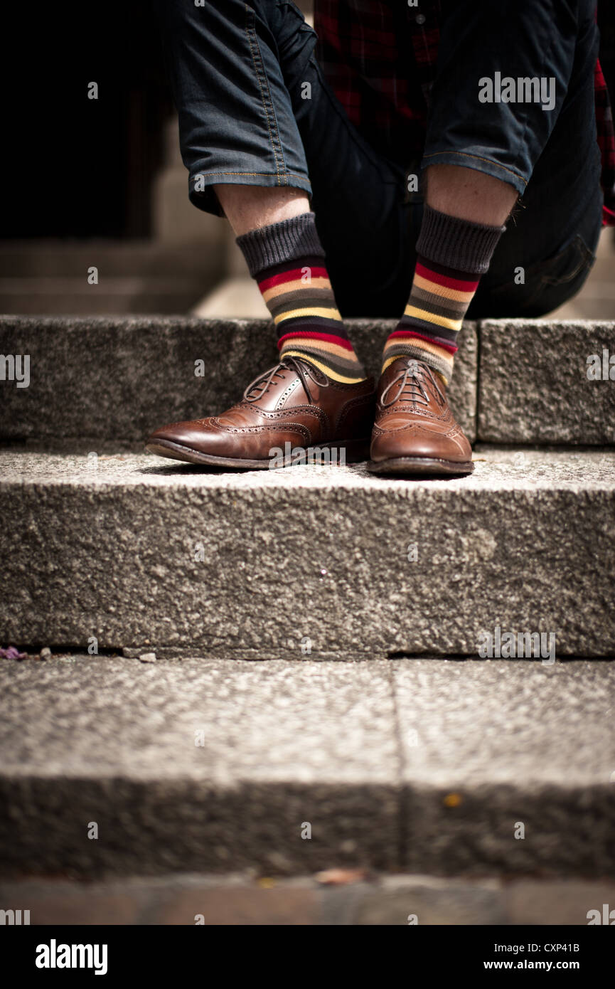 A man wearing brown brogues and funky stripy socks, sitting on some stone  steps Stock Photo - Alamy