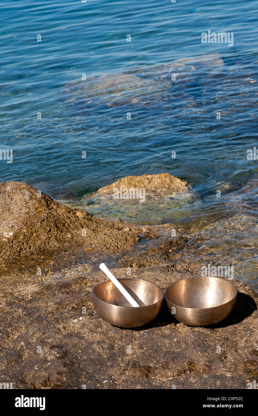 Tibetan singing bowls on a rock near the sea Stock Photo