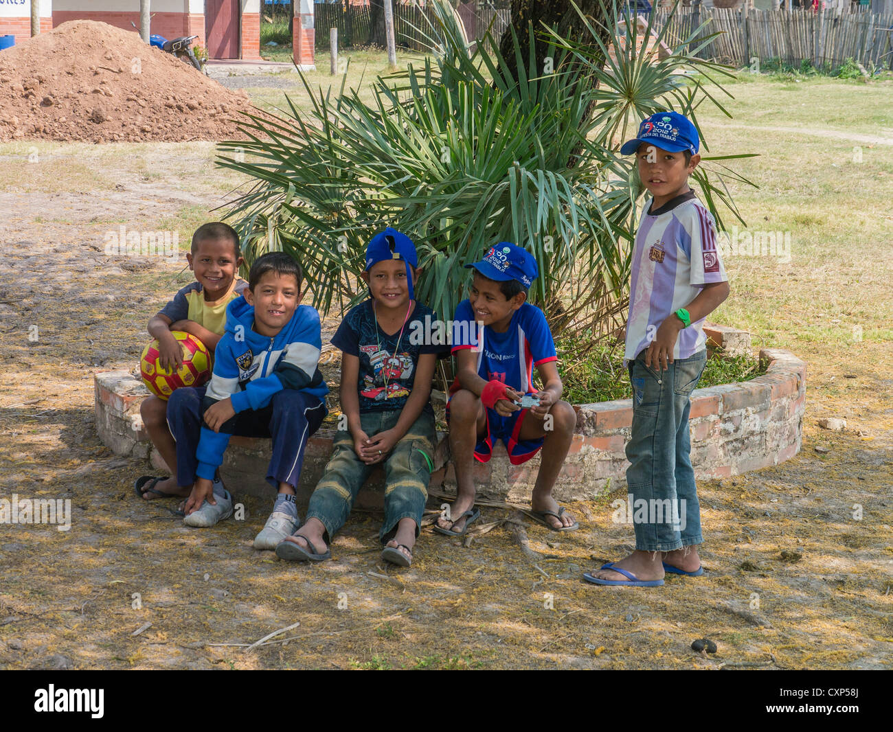 Five young boys, aged 8-10 years old, in the shade of a tree resting and smiling in the Chaco region of Paraguay. Stock Photo