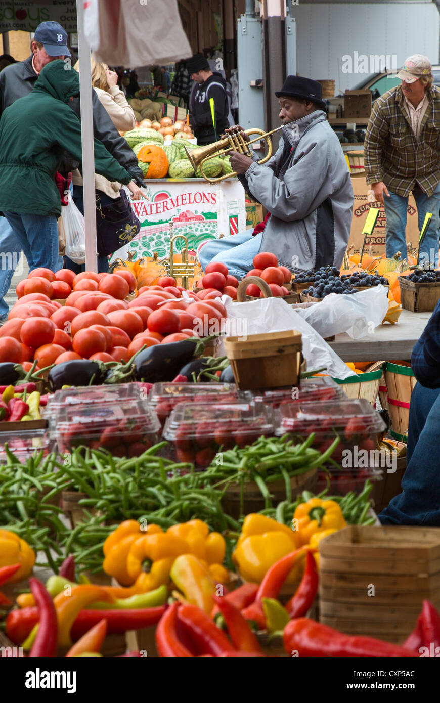 A man plays his trumpet amid the pumpkins on sale at Eastern Market in Detroit Stock Photo