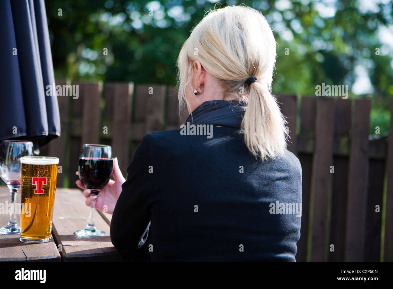 Rear view of a woman drinking beer and wine alone Stock Photo