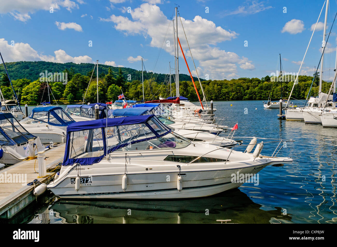 Gleaming white self drive motor boats with blue canopies float at their