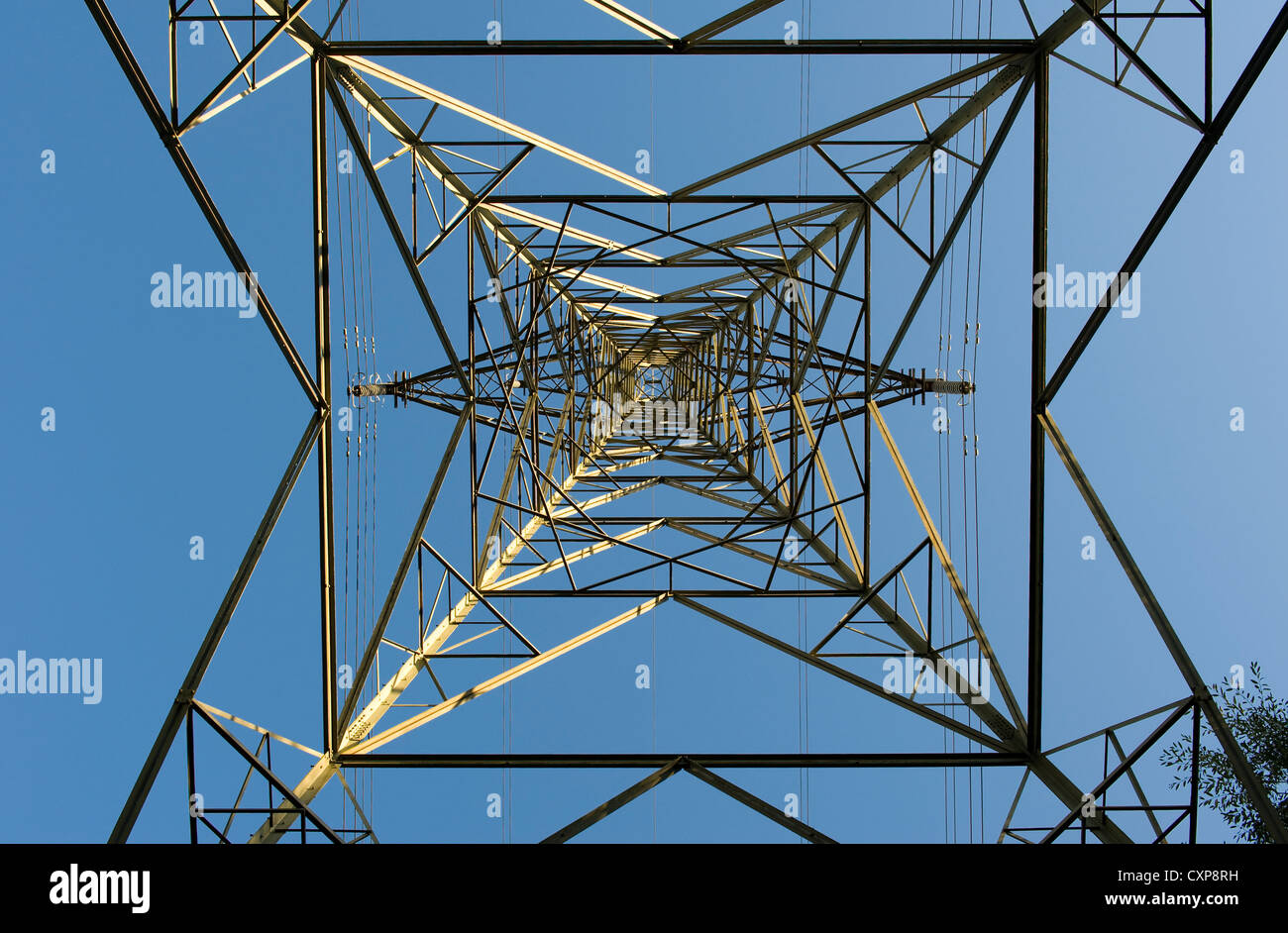 symmetrical electricity pylon from below against a blue sky Stock Photo