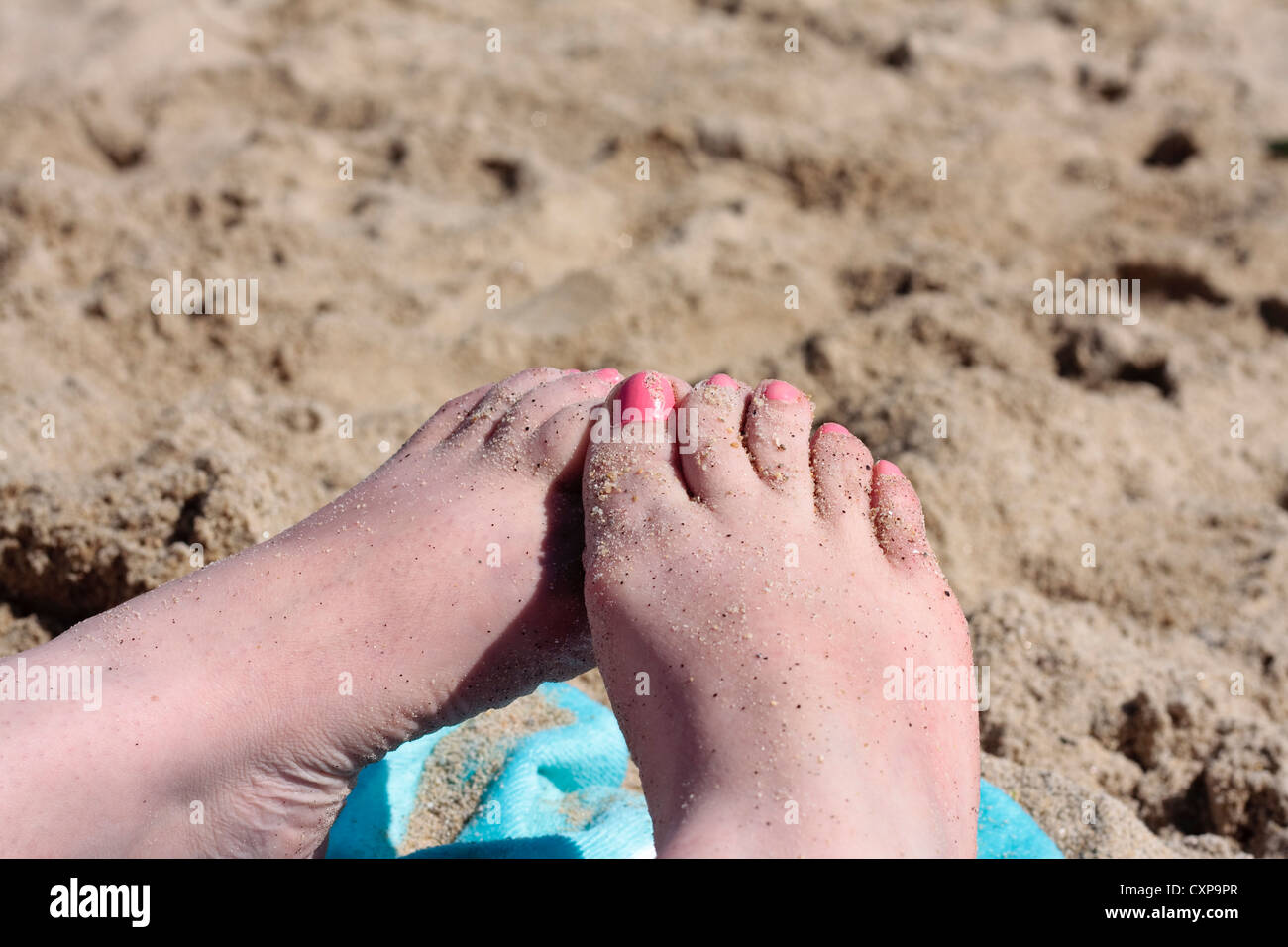 Sand covered female feet on a beach Stock Photo