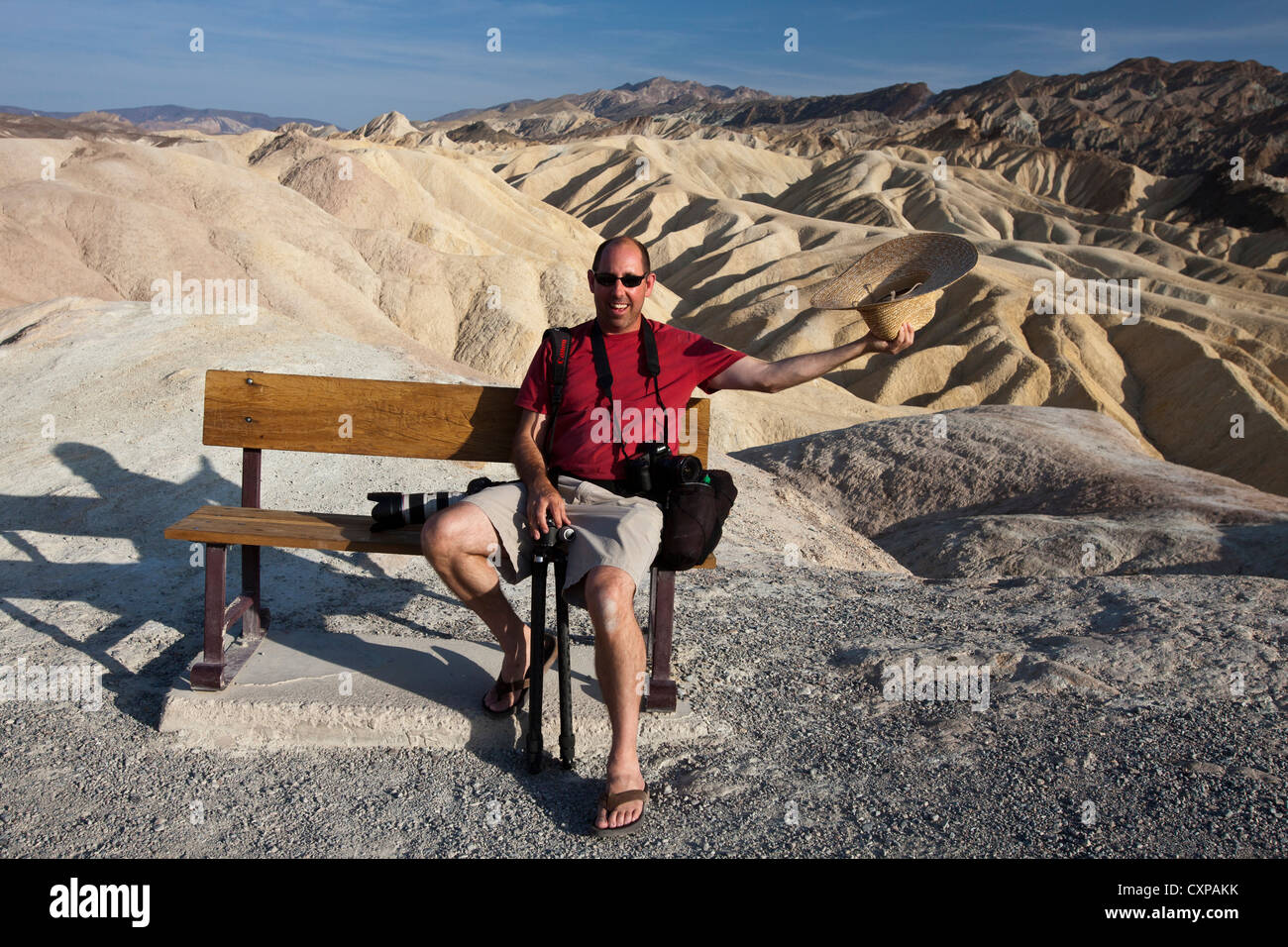 Adult male sits on park bench in front badlands Zabriskie Point Death Valley National Park California United States America Stock Photo