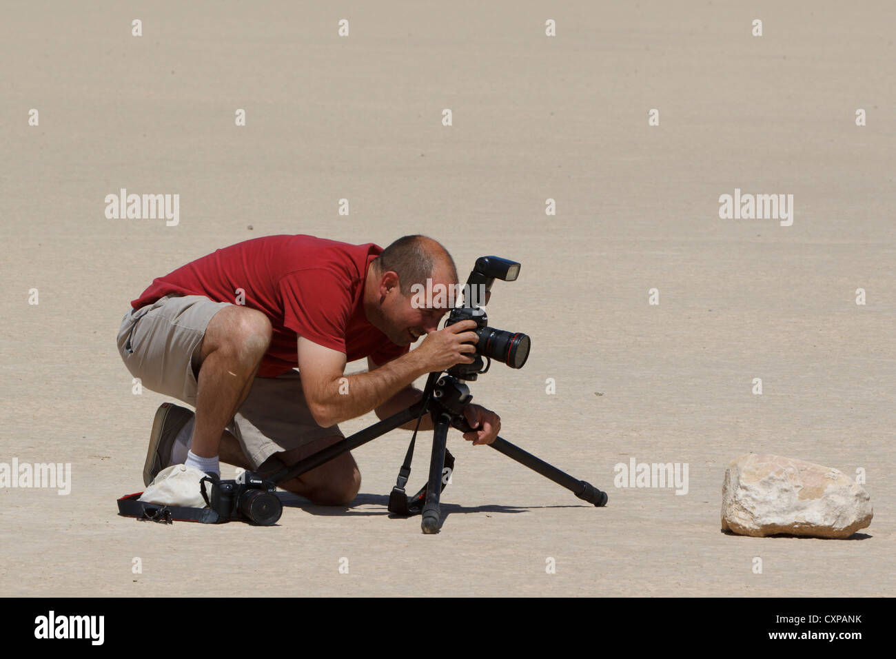 Adult male photographer taking pictures moving rock Racetrack Playa Death Valley National Park California United States America Stock Photo