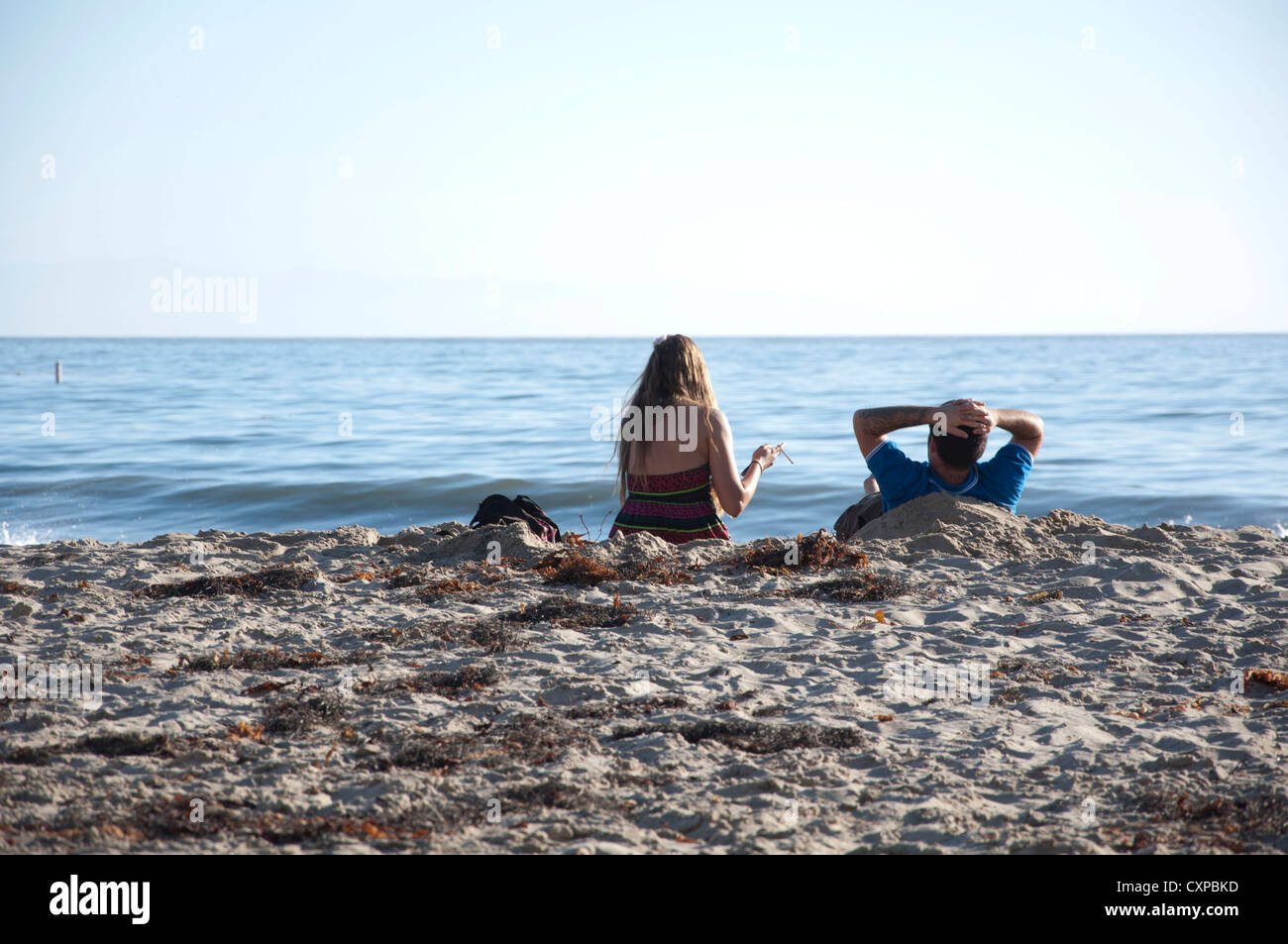 Couple on the beach relaxing Stock Photo - Alamy