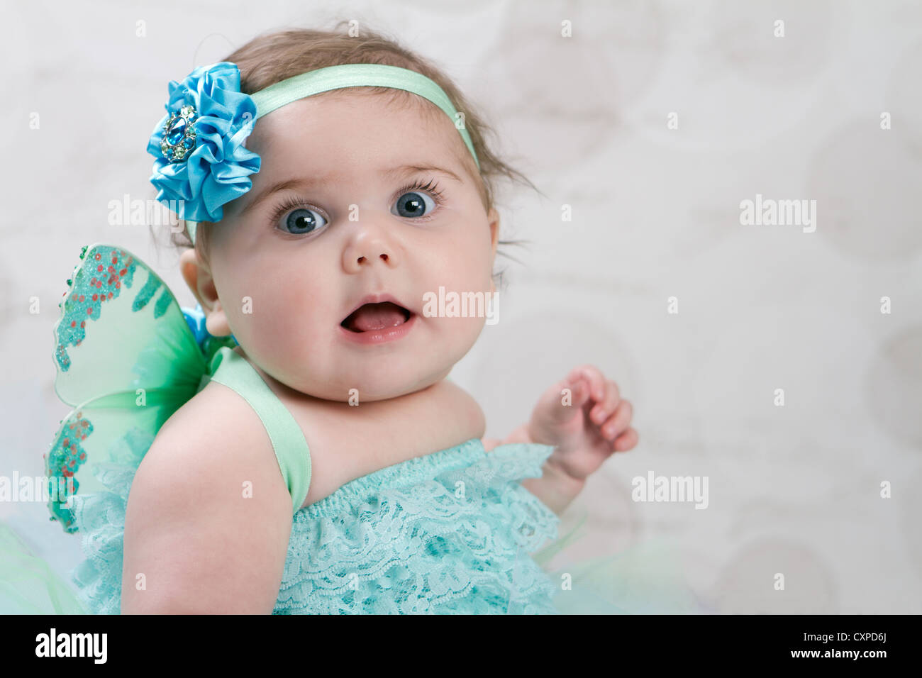 Baby girl 6 month old dressed as a pixie with fairy wings and turquoise ruffled bloomers. She wears a one flower headband. Stock Photo