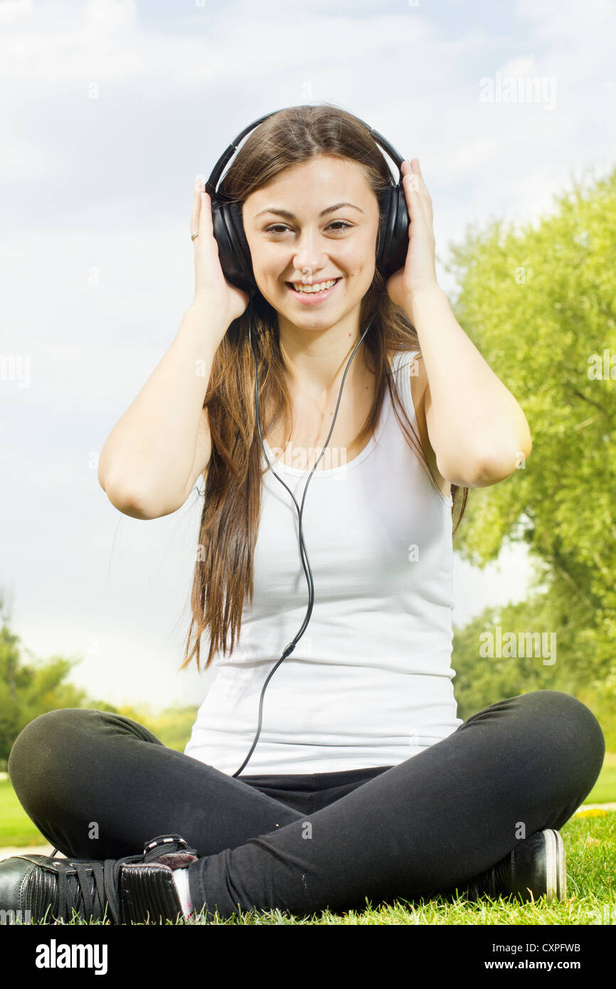 Happiness girl with headphones relaxing on green grass in the park ...