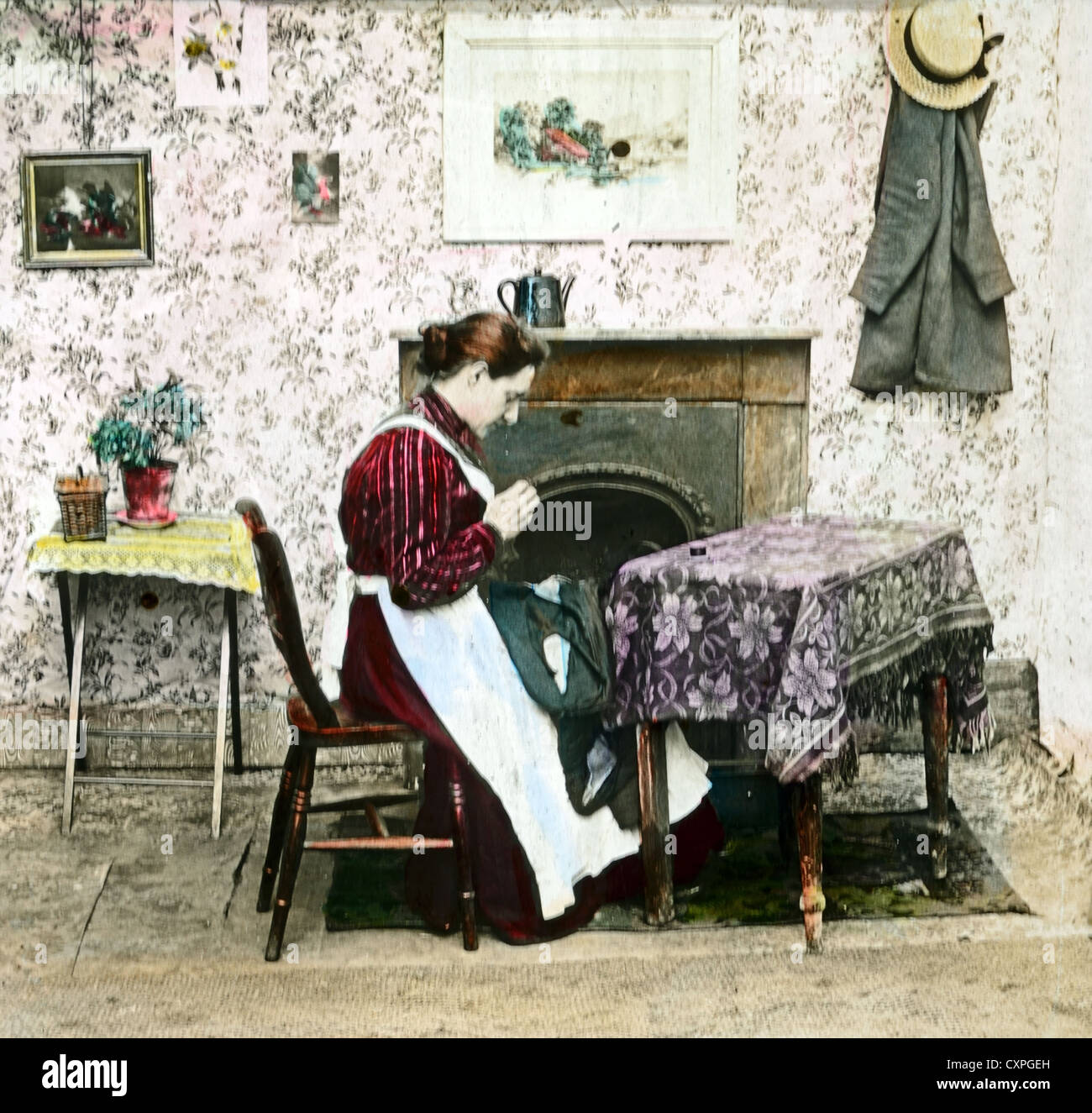 Victorian Woman Sewing by Fireplace in Living Room in Victorian England c1900 Stock Photo