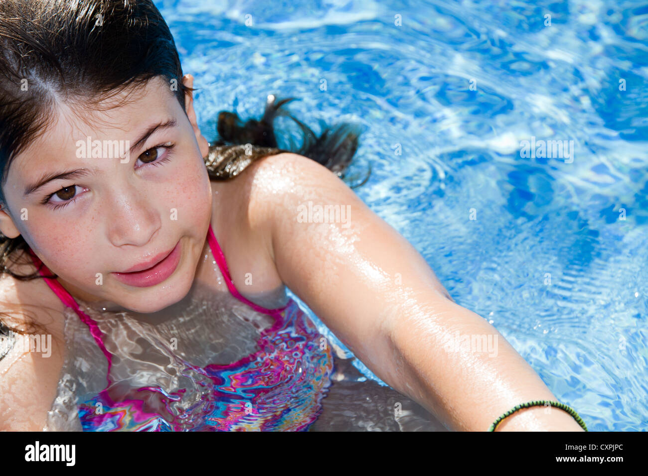 Young Girl Pre Teen Portrait Looking At Camera Swimming In Water Pool