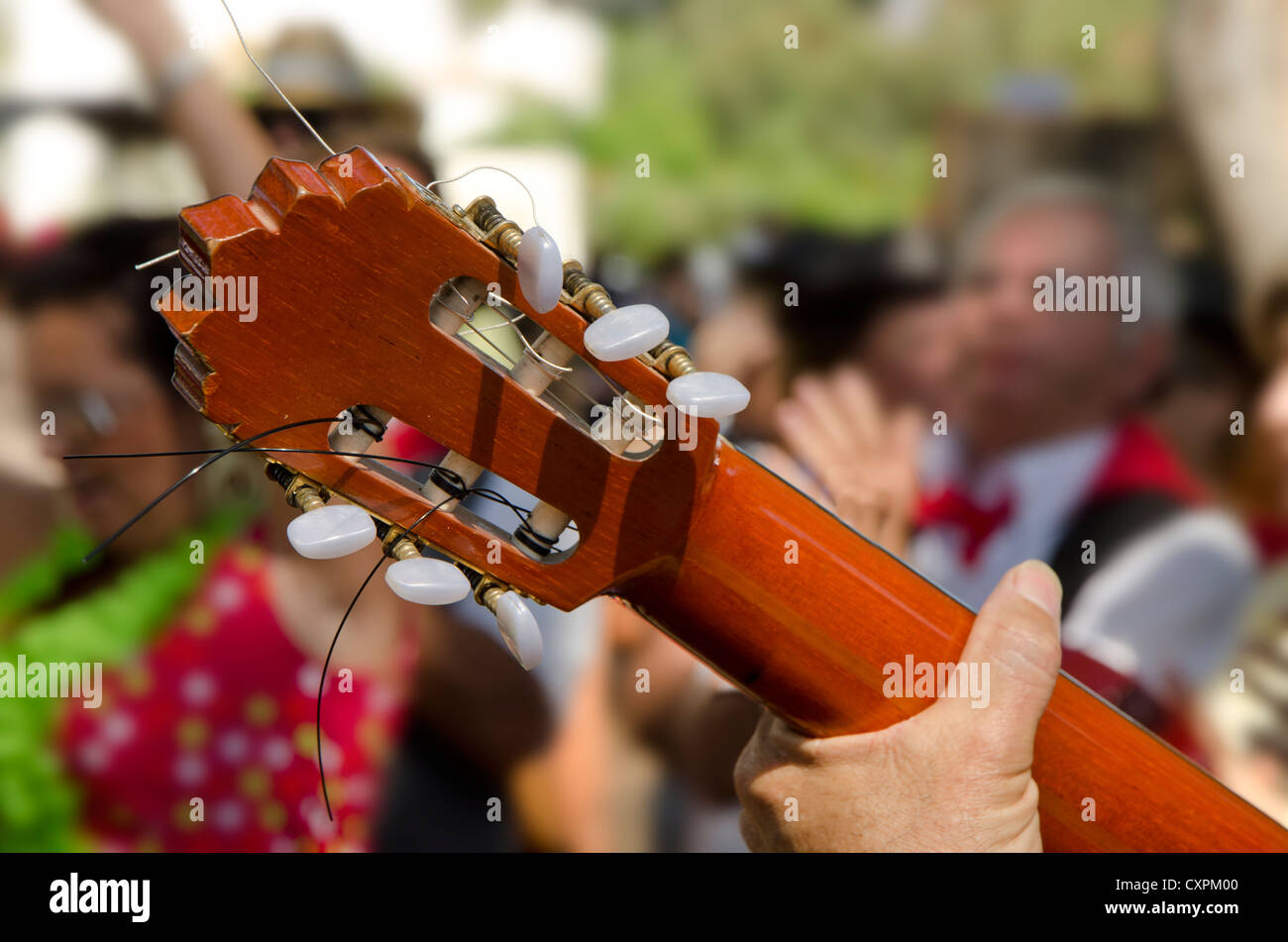 Neck of a Spanish guitar with dancing spaniards in the background in traditional clothing Spain. Stock Photo