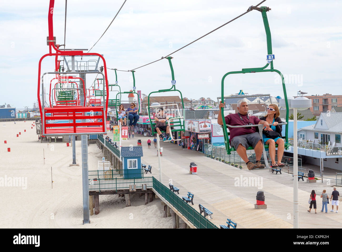 People Walking On An Ocean Boardwalk Surrounded By Food Games And