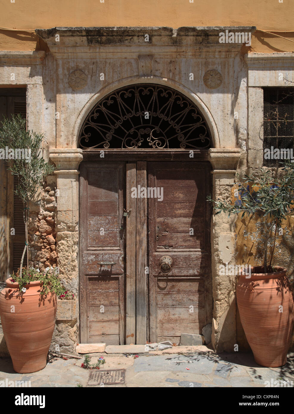 Painted doors in ornate gateway with large pots containing olive trees on either side, Hania/Chania, Crete, Cyclades, Greece Stock Photo