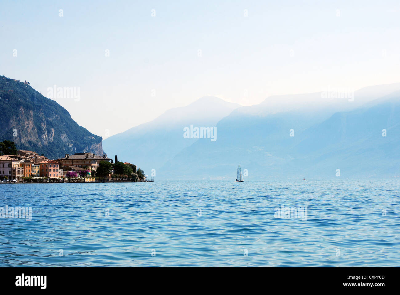 View of mountains, sail boat, and Gargnano from Lake Garda from the Lake District of Lombardy, Italy Stock Photo