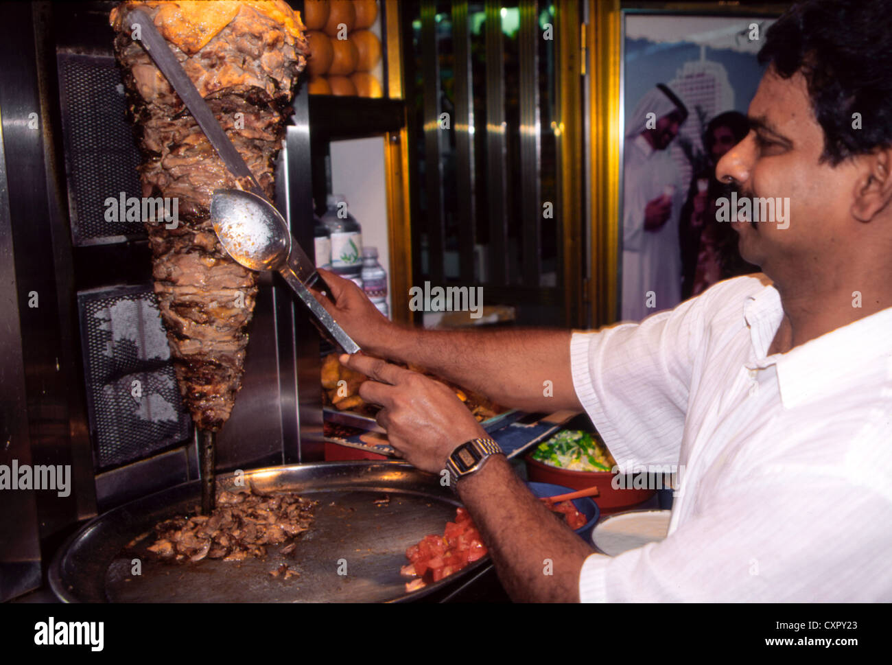 A man carving spitted beef or shawarma in a sidewalk shop in Abu Dhabi